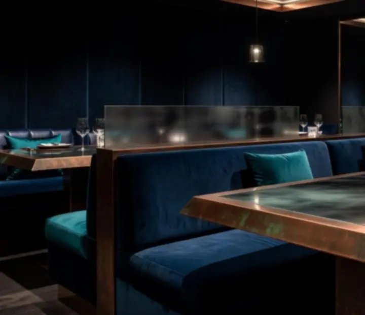 Restaurant interior featuring aged copper accents, smoked glass, and deep ocean lighting.